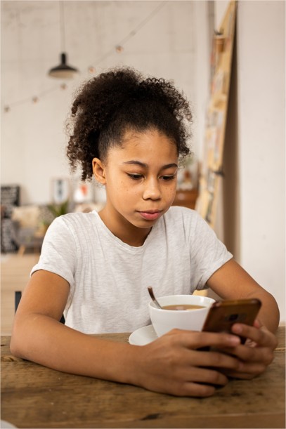 Jeune fille déjeune en regardant son téléphone
