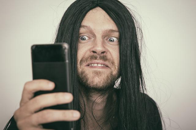 Homme qui regarde un smartphone avec une tete de psychopate